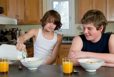 Two Brothers Serving Their Own Breakfast of Dry Cereal and Orange Juice – A typical USA High Carb Breakfast that is Low Fat