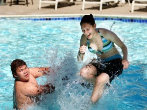 Two Teens Laughing and Swimming.  The swimmers are quite becoming, but somewhat overweight.