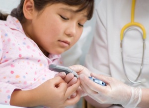 Elementary School Age Girl in the ER with Her Doctor Both Studying the Results on a portable Blood Sugar meter.    