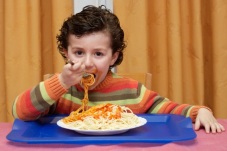 USA Child Eating School Lunch of Spaghetti.  The boy appears healthy and of average weight.