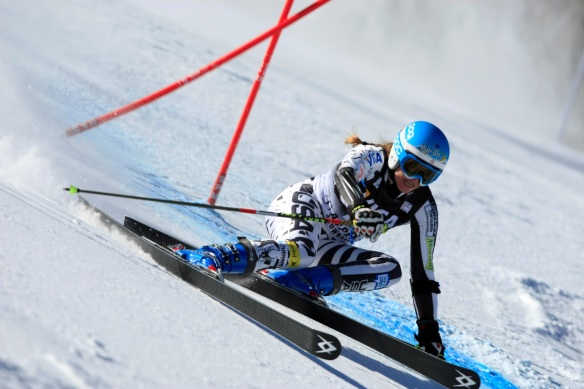 Female US Olympic Ski Team member racing past a gate